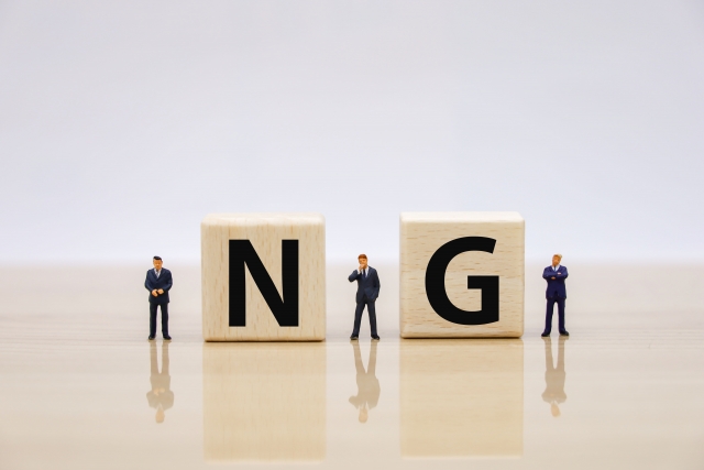 「NG」のブロックとビジネスマンのミニチュア