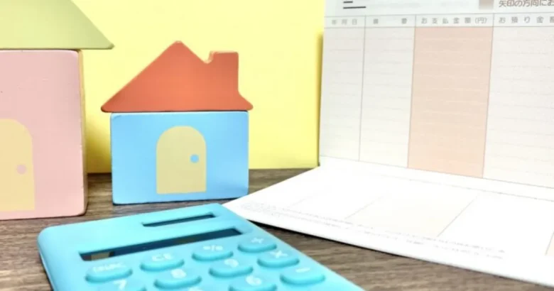 家の模型と電卓と通帳