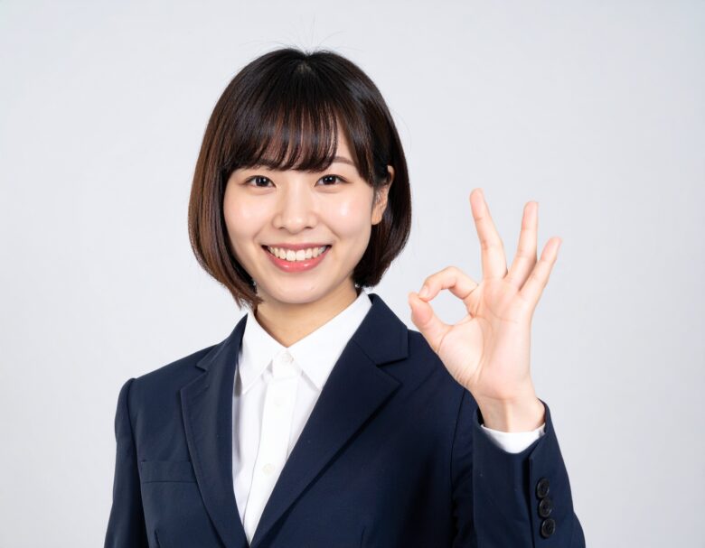 スーツを着た女性が笑顔でOKサインをしている