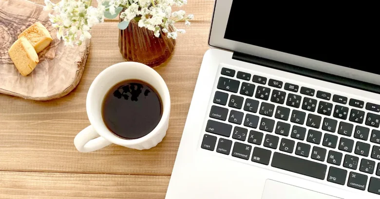 テーブルの上にパソコンとコーヒー、焼き菓子が置かれている