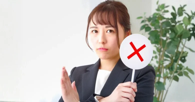 ✕マークを手に持つ女性