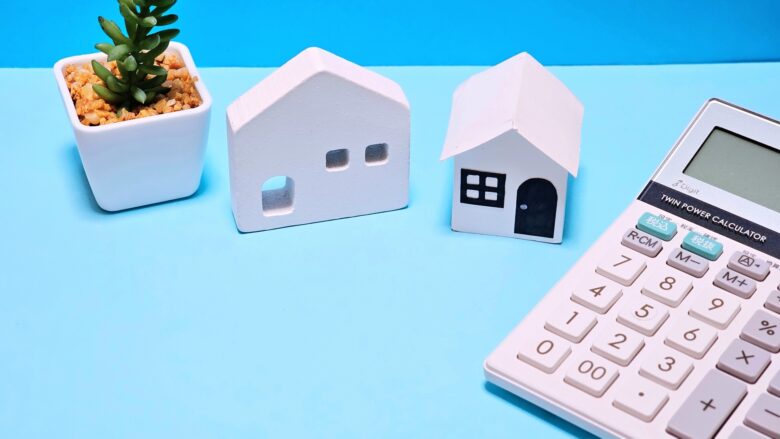 家の模型と電卓、観葉植物の鉢