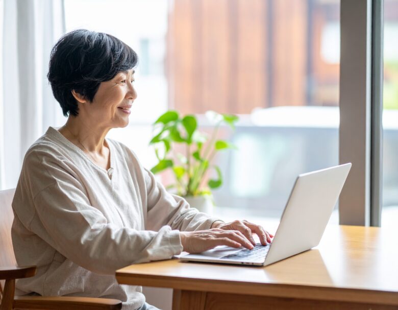 笑顔でPCを操作する中年女性