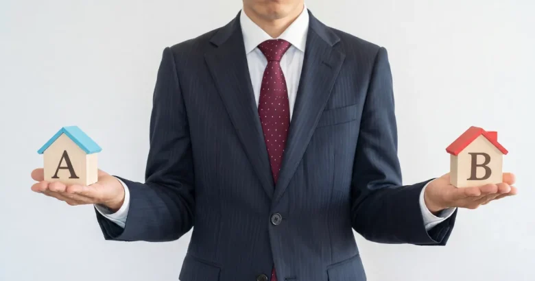 スーツを着た男性が「A」「B」とそれぞれ書かれた家を両手に持っている