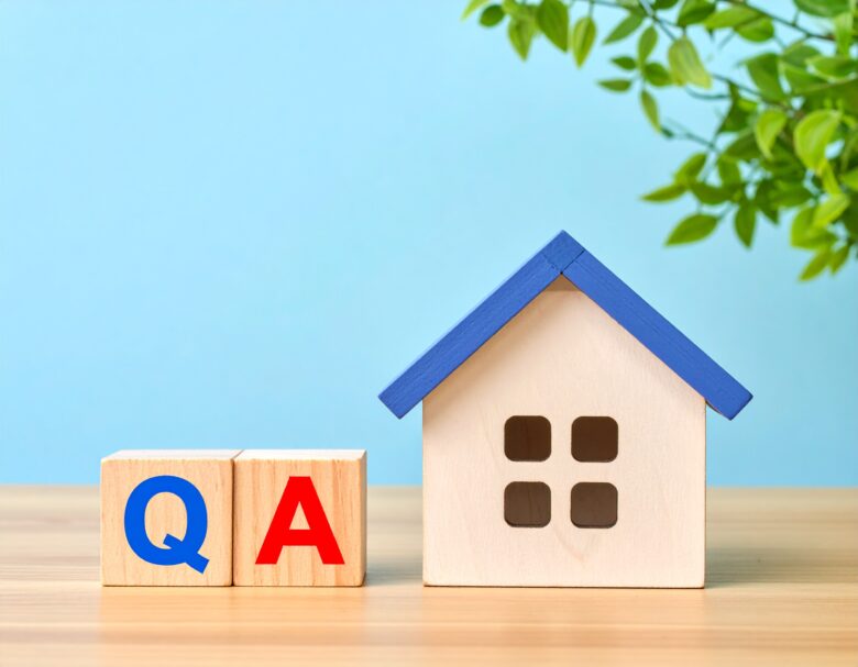 机の上にミニチュアの家と青色で「Q」、赤色で「A」と書かれたブロック