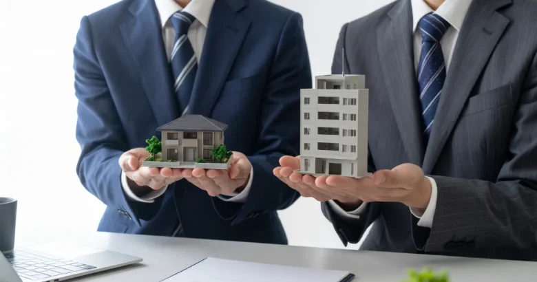 一戸建ての模型とマンションの模型を持つ2人のビジネスマン