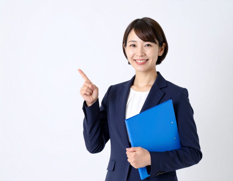 スーツを着た日本人女性が片手にバインダーを持ち、もう一方の手は人差し指で上を指している様子。