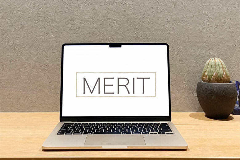 机の上にノートPCが開かれておかれており、画面には「MERIT」と書かれている。サボテンが置かれている