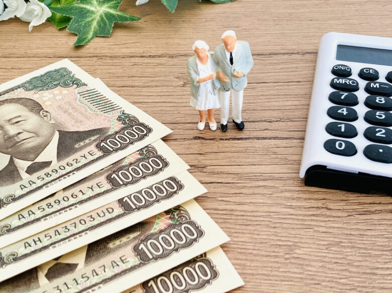 テーブルの上に夫婦の模型と5枚の万札と電卓が置かれている