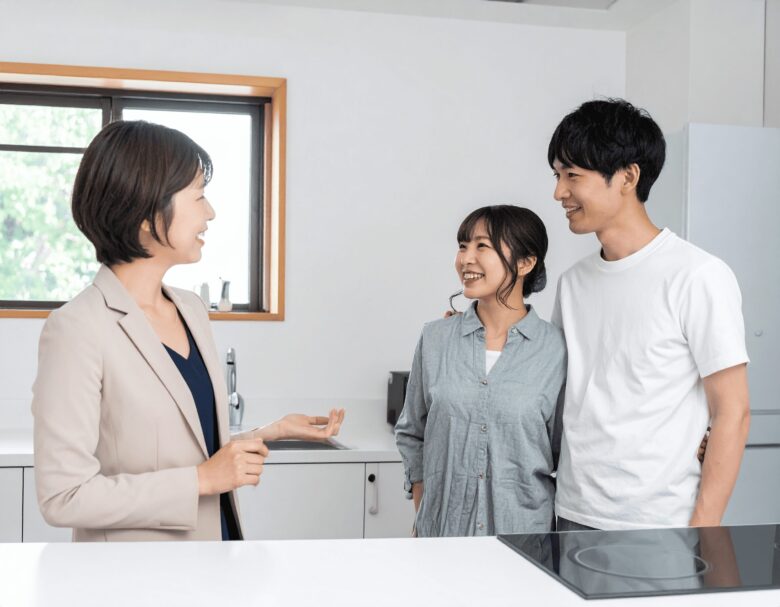 夫婦が住宅の内見をしている。キッチンで女性が説明をしている。