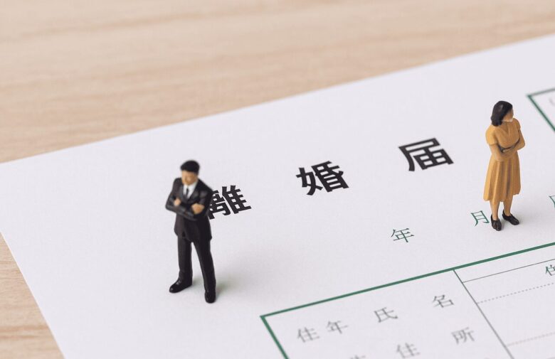 離婚届の上に人形の夫婦が乗っている。二人は別々の方向を見ている。