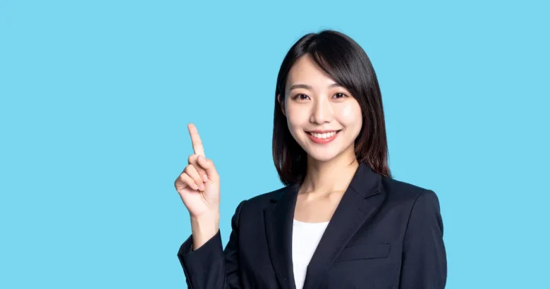 笑顔で人差し指を上に向けて指している女性