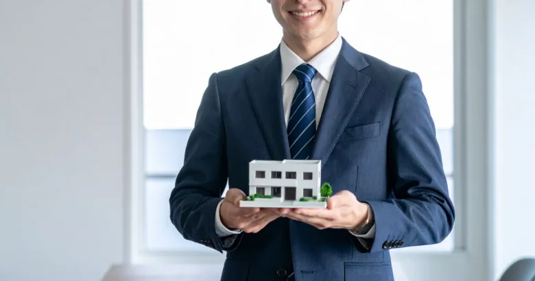 マンションの模型を持っているビジネスマン